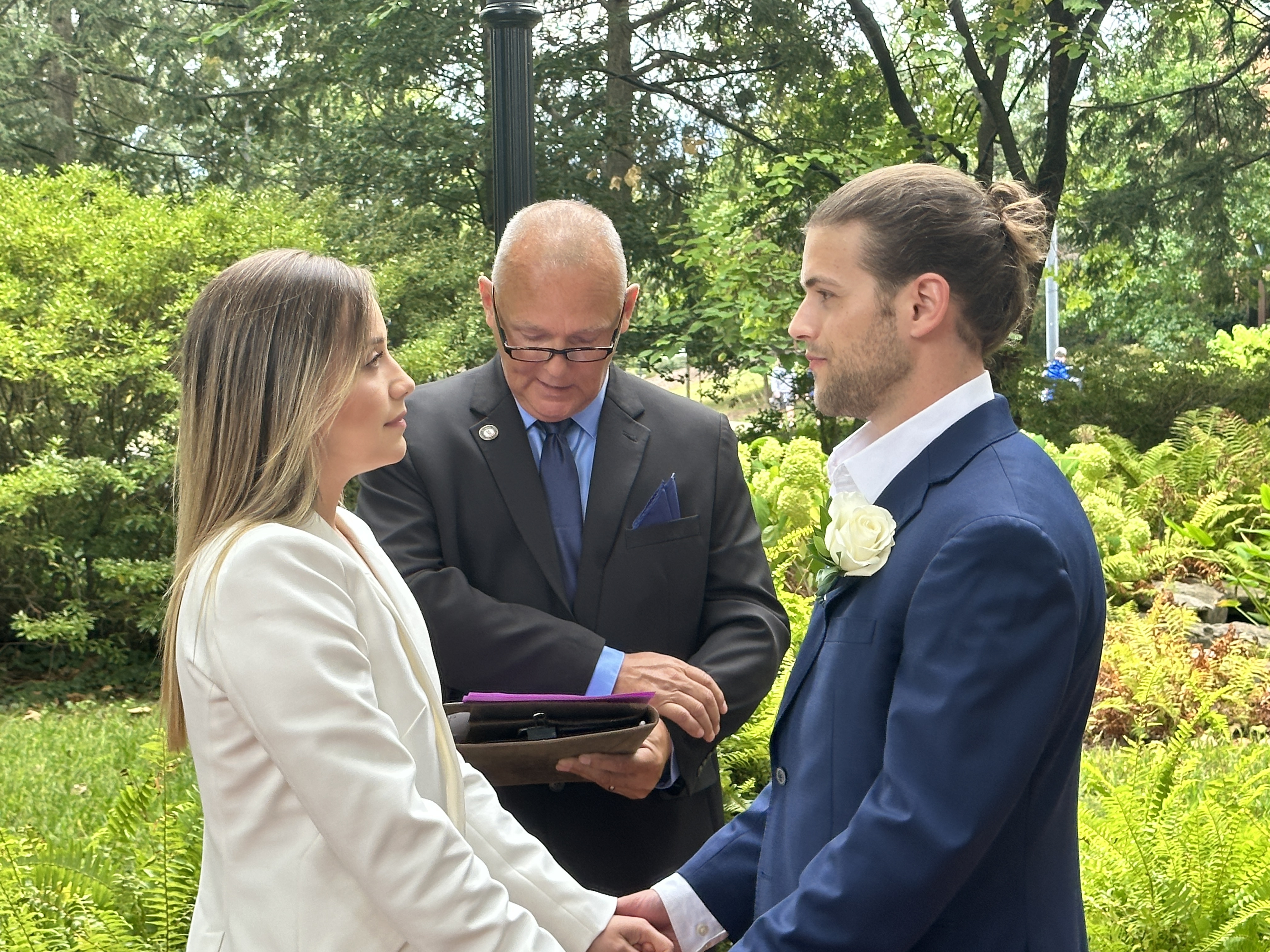 Kevin officiating intimate garden ceremony — couple exchanging vows
