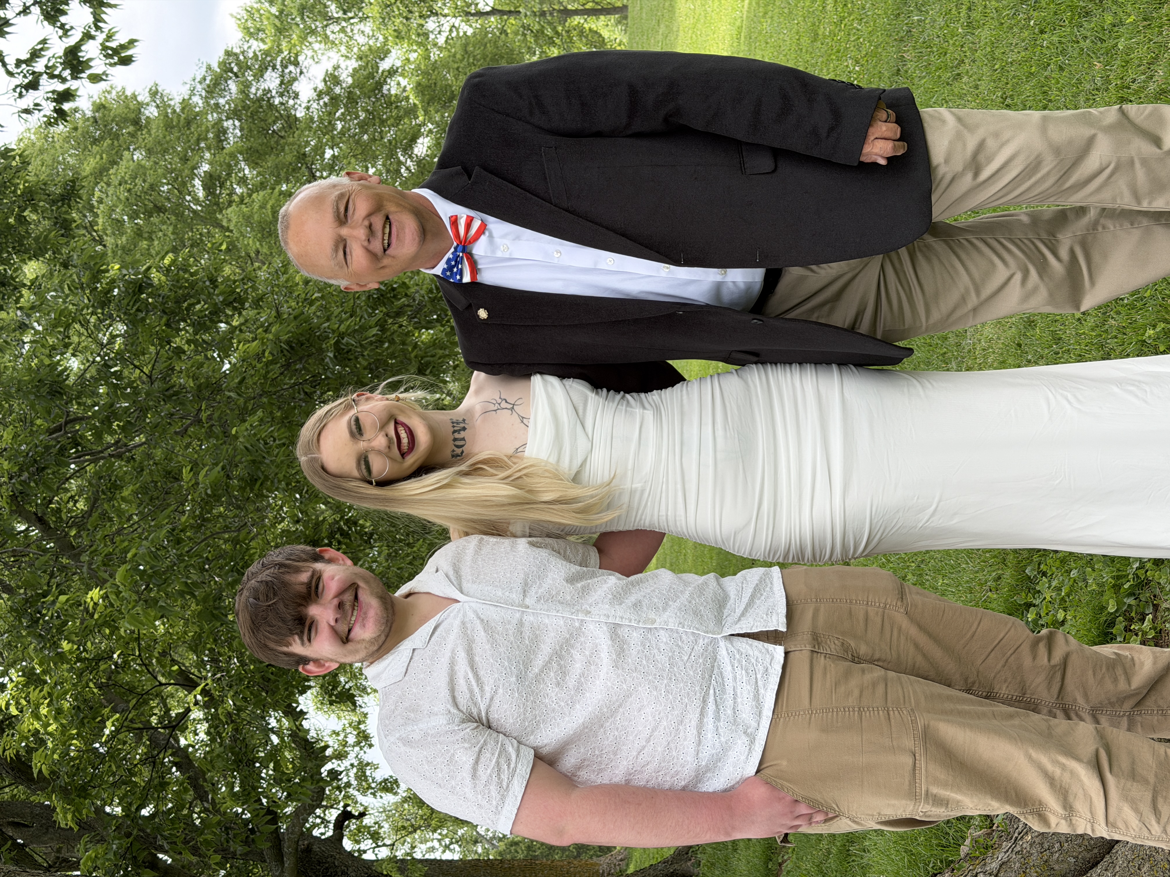 Kevin with bride and groom outdoors in green park