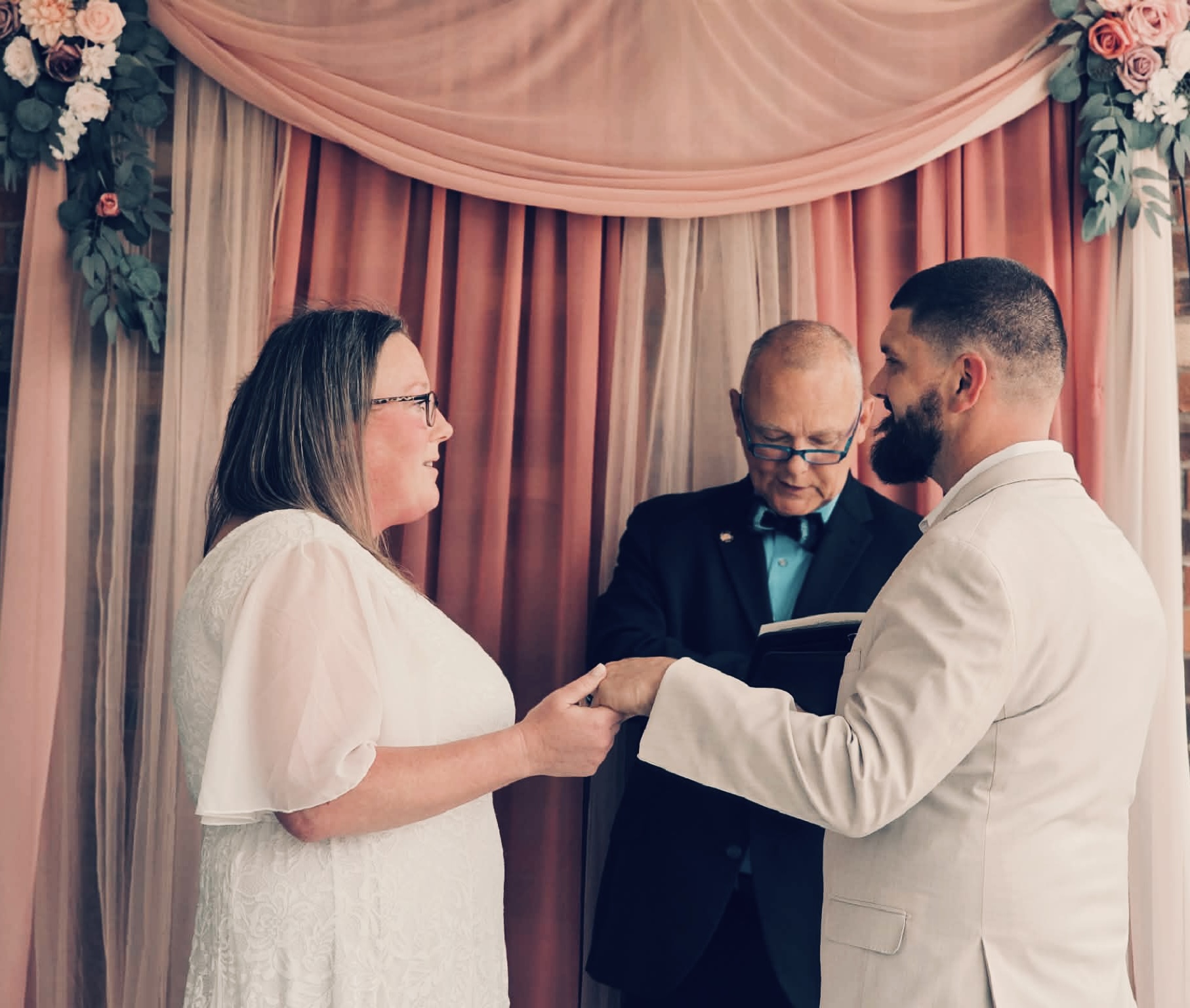 Kevin officiating ceremony under pink floral arch
